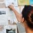 Female Student Adding Item To Bulletin Board