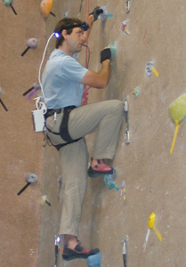 Weihenmayer climbing on a gym rock wall in Golden, CO, with the help of the BrainPort device.