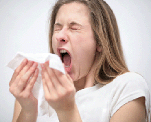 Photo of a young woman sneezing.