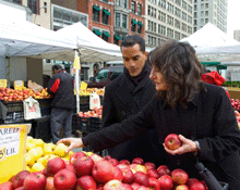 Photo of two people at an outdoor fruit stand.
