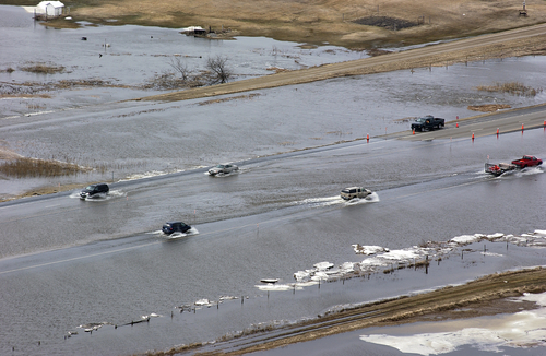 cars drive through a flooded roadway