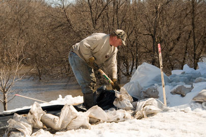 A resident from Oxbox, ND realigns sand bags around the back of his home as part of the town's preparations for possible flooding by the Red River flooded. The stake is the line that signifies the level the river must reach to flood his home. Oxbox citizens are preparing for the possibility of additional flooding later in the week. Photo by Patsy Lynch/FEMA