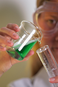 a photo of a scientist measuring a green liquid.