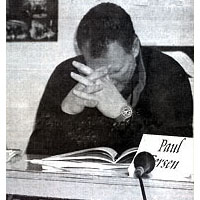 Photo of a man at a table with hands in front of his face and his eyes closed