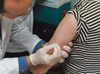 Smallpox vaccination dilution study:  Dr. John Treanor uses a two-pronged needle to deliver the smallpox vaccine into the arm of a volunteer.
