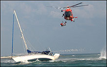 Coast Guard helicopter pulling people from capsizing sailboat