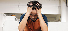 A teenage boy sitting on a sofa looking stressed