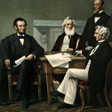 Lincoln seated at a table with other men.