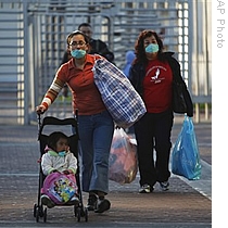 People, wearing face masks as a precaution against swine flu, walk after crossing from U.S. to Mexico at the San Ysidro crossing port in Tijuana, Mexico, 30 Apr 2009