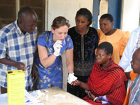A CDC female employee (as the focal point), surrounded by six Bungu Dispensary health workers, demonstates how to take a blood sample.