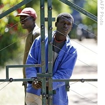 Two men stand by gates of farm they seized from white farmers in Chegutu, 120km south west of Harare, 17 Apr 2009