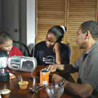 Photo of family sheltering in place, sitting around table listening to radio