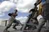 Senior Airman Michelle Metz and fellow airmen rotate a hydraulic jack.