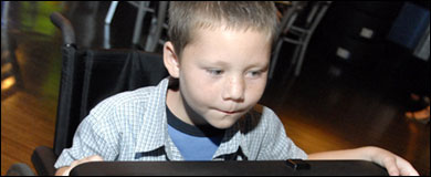Photo: A boy in a wheelchair play a video game.