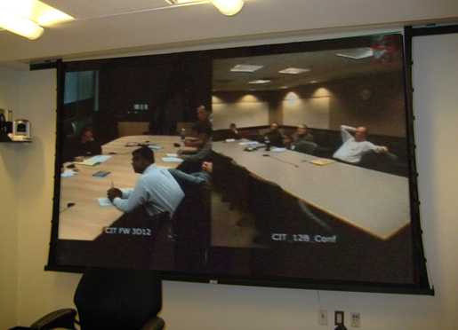 Photo of pull-down screen showing video image of two seperate conference rooms