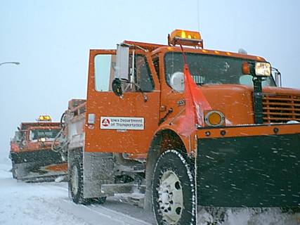 Snow plows clearing the highway during a winter storm.
