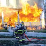 Firefighters using hose at house fire