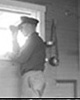 Member of the U. S. Coast Guard looking through binoculars out of a window at the Old Chicago Coast Guard Station