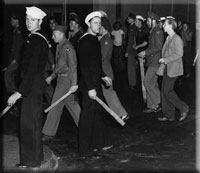 U.S. armed forces personnel with wooden clubs on street during 'zoot suit' riot,.