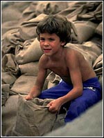 Photo of a boy carrying a sand bag.