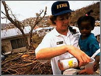 Photo of a FEMA employee giving a child juice.