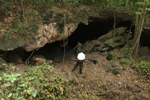 Two people standing at the python cave opening, home of the fruit bats thought to harbor Marburg virus.