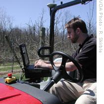 Carnegie Mellon University Research Programmer Brad Hamner gives computer instructions to an autonomous electric vehicle at Half Crown Hill Orchard