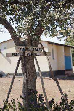 HIV/AIDS is Real – Protect Yourself” sign is posted on a tree.