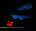 Photo of luminescent porous silicon nanoparticles in a vial illuminated with ultraviolet light.