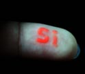 Photo of silicon element symbol spelled out on a fingertip with luminescent silicon nanoparticles.