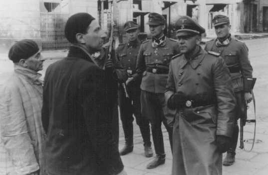 ایس۔ ایس اور پولیس کا لیڈر جوئرگن سٹروپ وارسا گھیٹو کی بغاوت کے دوران گرفتار کئے گئے دو یہودیوں سے پوچھ گچھ کر رہا ہے۔ پولینڈ، 19 اپریل- 16 مئی 1943۔