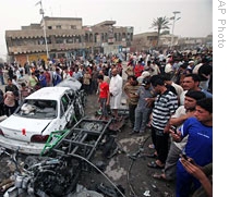 People gather around wreckage of car destroyed in a car bombing in Sadr City, Baghdad, 29 Apr 2009