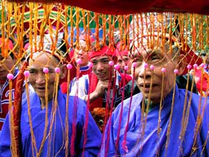 Men watch a procession from under an umbrella during spring festival in Binh Minh, Vietnam,  March 4, 2001. [© AP Images]