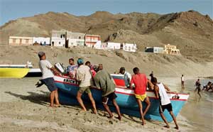 Fishermen drag a small boat up the shore in Sao Pedro Bay, Sao Vicente, Cape Verde. September 8, 2000. [© AP Images]