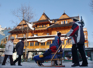 Tourists walk on street with traditional house in background, Zakopane, Poland, January 14, 2006. [© AP Images]