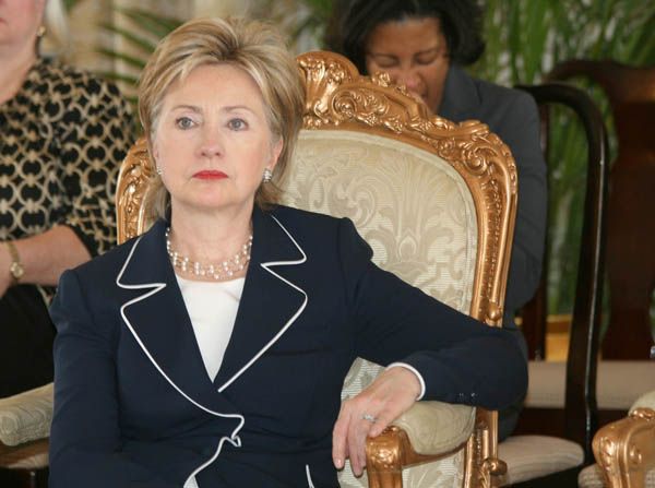 Following a speech at the National Palace in Haiti, Secretary of State Hillary Rodham Clinton listens to President of the Republic of Haiti, Rene Preval give his speech to the press before the press conference.