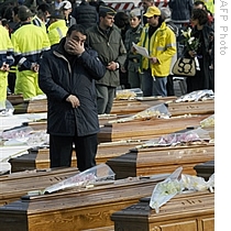 Relatives and friends gather in the vast square courtyard of a police training center where coffins were arrayed prior the state funeral of the dead of the April 6 eathquake in the Abruzzo capital L&amp;#39;Aquila, 10 Apr 2009