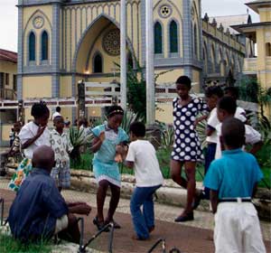 Children play a skipping game in front of cathedral built during colonial times in Malabo, Equatorial Guinea, August 25, 2002. [© AP Images]