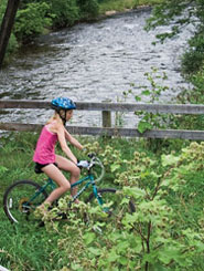 Photo - girl biking along a stream in Vermont