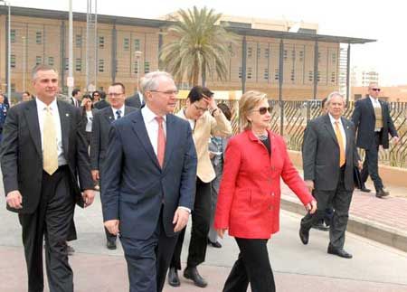 Date: 04/25/2009 Description: Diplomatic Security special agents (left and right) protect U.S. Secretary of State Hillary Clinton as she walks with U.S. Ambassador Christopher R. Hill on the grounds of the new U.S. Embassy in Baghdad, Iraq, April 25, 2009.   State Dept Photo