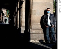 A man, wearing a face mask as a precaution against the swine flu, stands next to the Zocalo Plaza in Mexico City