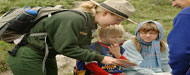 A park ranger is showing two kids how to read a map.