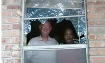 Photo: Man and woman looking out of a broken window.