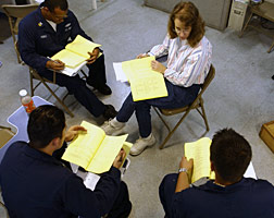 A group of sailors review course material with their teacher.