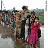 Cyclone-affected children lined up in the rain waiting for food in the Shwepoukkan area of Burma, 25 May 2008