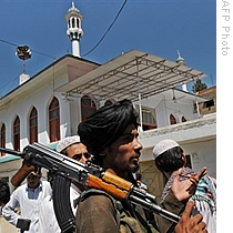 An armed Pakistani Taliban chats with residents outside a mosque in Buner district of the troubled Swat valley, 23 Apr 2009