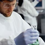 Lab worker with a beaker of green fluid