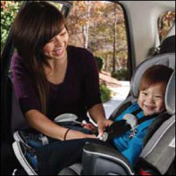 Woman fastening her child in a car seat