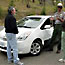 A ranger and two visitors engage in a discussion standing in front of a Toyota Prius.