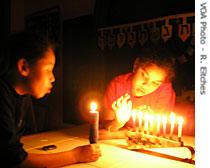 Two children are fascinated by a Hanukkah menorah and lighted candles